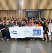 Group of females in HVAC industry holding giant TCC banner
